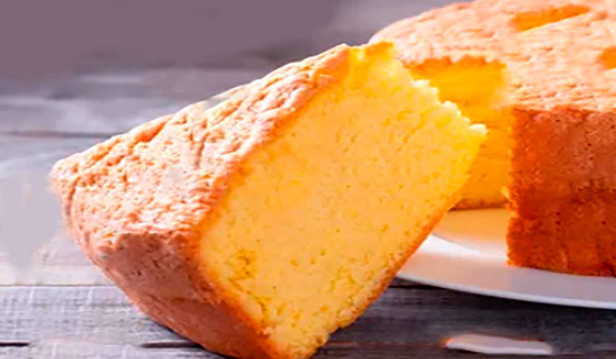 Pedaço de bolo fofo de iogurte sem farinha servido em um prato branco, ideal para a Dieta Dukan, acompanhado de um café